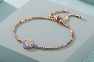 Dettaglio del bracciale con moneta Sagittario in oro rosa, smalto blu e catena regolabile