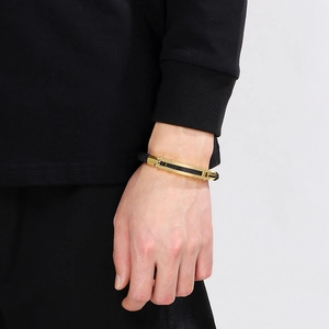 Detail of men's stainless steel gold bracelet with black carbon fiber inlay on wrist