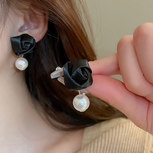Detail shot of vintage black velvet rose earrings with a white pearl on a model