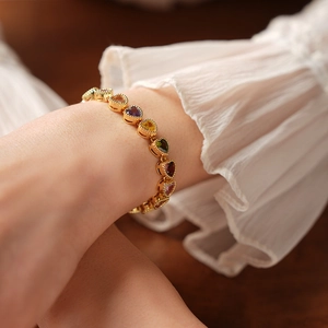 Close-up of 18K gold plated heart bracelet with colorful gemstones on female wrist