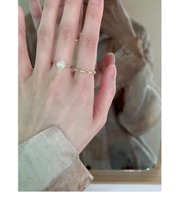 Close-up of elegant gold pearl ring and diamond-set band worn on finger by a mirror