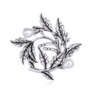 Detail view of silver metal leaf brooch with two white pearls and vintage texture