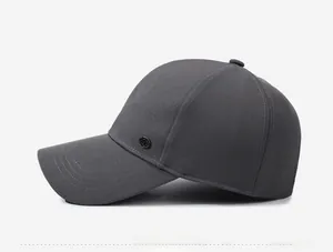 Side view of dark gray cotton baseball cap with a circular metal logo and curved brim