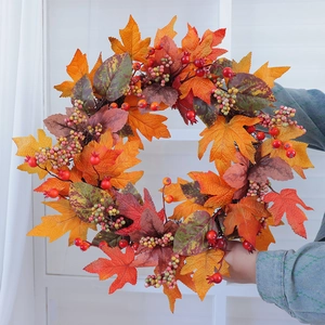 Autumn wreath with maple leaves and berries held by a person for harvest decor