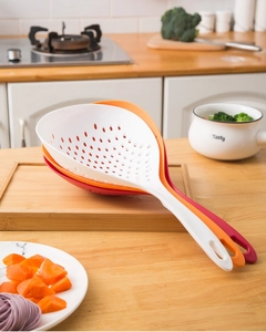 Detailed view of stacked nylon colander spoons in white, orange, and red on a wood board