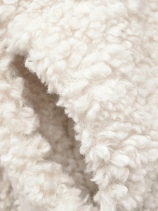 Makrotextur aus cremefarbenem Kunstfell mit weichen, lockigen Lammwolldetails