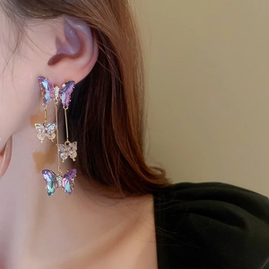 Detail of purple crystal butterfly tassel earrings with gold metal on model