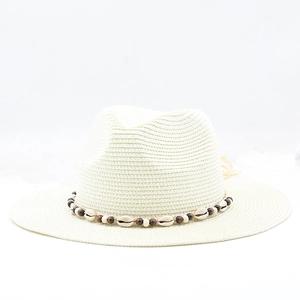 Close-up of bohemian straw hat featuring natural sea shells and ethnic beaded ribbon trim