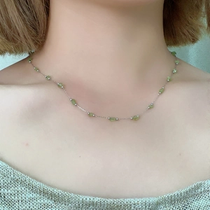Detail view of peridot green natural stone necklace on model collarbone area