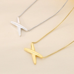 Close-up of minimalist X-shaped pendants in gold and silver finish with box chains