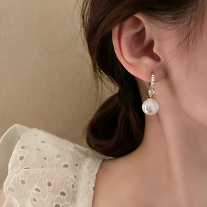 Elegant gold drop earrings with shimmering pearls and zircon accents on a female model