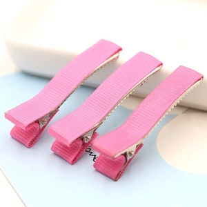 Three pieces of pink ribbed ribbon-wrapped metal alligator hair clips on a soft blue background