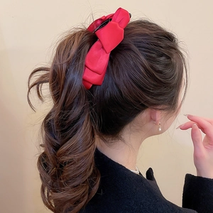 Détail d'une grande pince à cheveux nœud en satin rouge pour une coiffure élégante