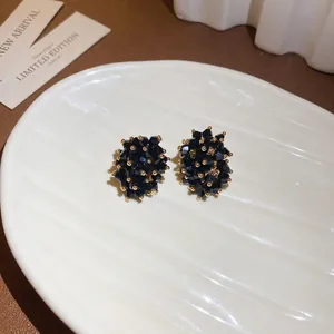 Chic black faceted crystal cluster stud earrings with gold accents on white tray