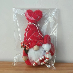 Detail of plush Valentine gnome with red sequined hat and beaded legs in packaging