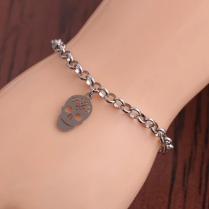 Minimalist stainless steel bracelet with hollow skull charm on wood background