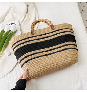 Detail of woven straw tote bag with black stripes and authentic bamboo handles