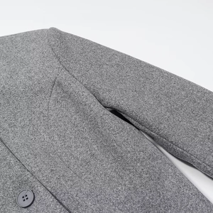 Detailed view of the shoulder seam and dark grey button on a grey wool coat texture