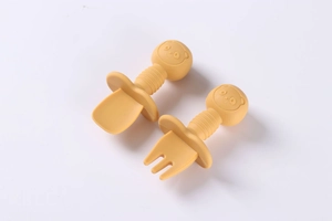 Detail of yellow silicone baby spoon and fork set with bear head handle and safety guard