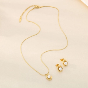 Elegant gold-plated shell pearl jewelry set featuring necklace and earrings on silk cloth