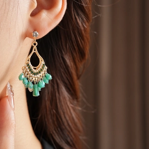Detail of drop tassel earring with green beads and pearls on model