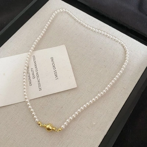 Vue détaillée d'un collier de perles blanches avec un fermoir à boule dorée polie