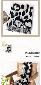 Close-up of soft faux cashmere scarf with black and white cow print and fringe detail