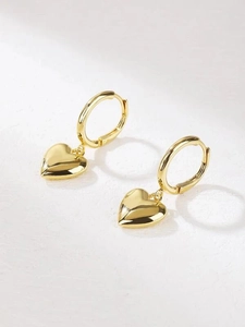 Macro view of polished gold 3D heart charms on classic hoop earrings with a mirror finish
