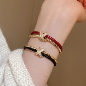 Détail d'un bracelet croisé doré avec zircons micro-pavés et cordons tressés au poignet