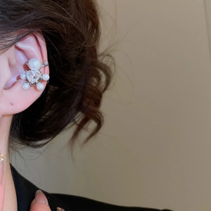 Close-up of elegant bear-shaped ear cuff featuring heart zircon and pearls on ear