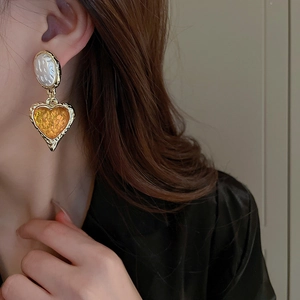 Macro detail of amber resin heart earring with golden trim on a model profile
