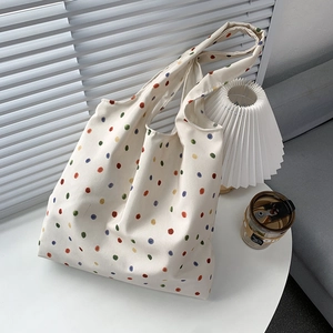 Detailed lifestyle shot of a large canvas tote bag with colorful polka dots on a white table