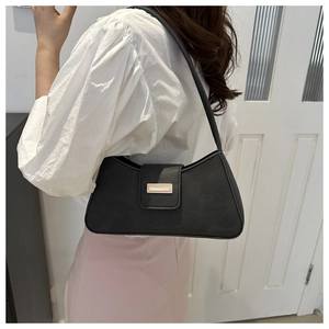 Close-up of black faux leather baguette bag featuring a stylish golden rectangular buckle