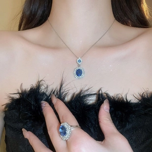 Detail of luxury oval blue gemstone necklace and ring set with white diamond halo