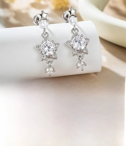 Detail of star-shaped titanium steel cartilage piercing studs with sparkling zircon pendants