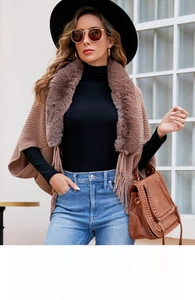 Close-up of the plush faux fur collar and knit tassel details on the brown winter poncho
