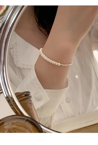 Close-up of s925 silver bracelet featuring white freshwater pearls and a heart charm