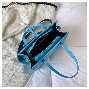 Detail view of bright blue tote bag with inner zipper compartment and wide shoulder strap
