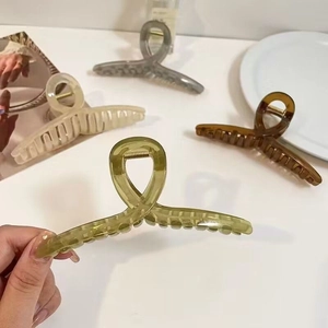 Detail of four large earth-tone hair claws in green, grey, cream, and amber finishes
