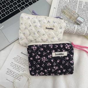 Floral quilted cosmetic pouches in white and black patterns with woven zipper details
