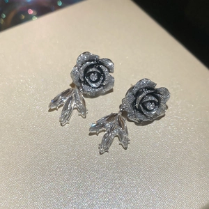Dettaglio di orecchini a fiore in resina con tre pendenti a foglia di cristallo argento