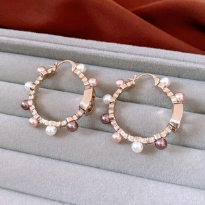 Macro detail of 18K gold plated hoop earrings with white and pink pearls in a jewelry box