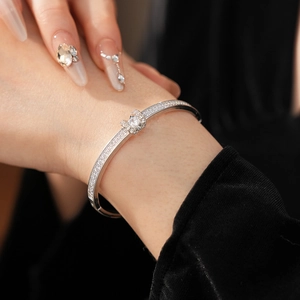 Macro detail of silver-toned bangle featuring micro-paved zircons and a central crystal buckle