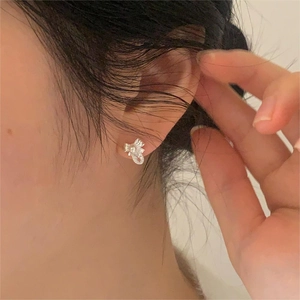 Detailed close-up of a silver bow knot earring featuring a delicate pearl and zircon stone