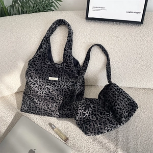 Detail of leopard print tote and crossbody bag set on a sofa with lifestyle accessories