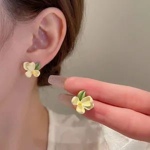 Floral stud earrings with yellow petals and green leaves in fresh forest style design