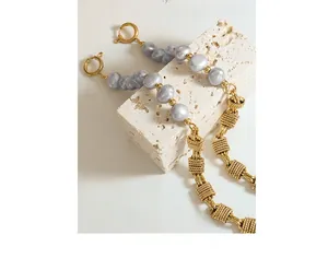 Macro view of grey freshwater baroque pearl and textured gold chain link with clasp