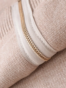 Detailed macro view of the gold metal zipper and premium beige knit fabric texture