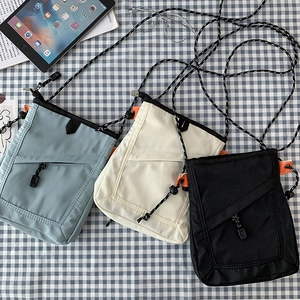 Detailed view of canvas crossbody bags in blue, beige, and black with rope straps
