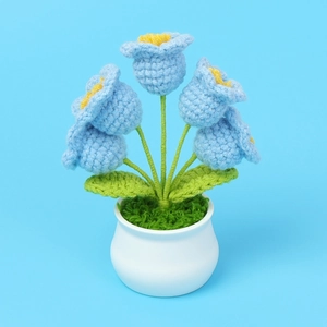 Macro shot of handcrafted blue crochet lily of the valley flowers in a white ceramic pot